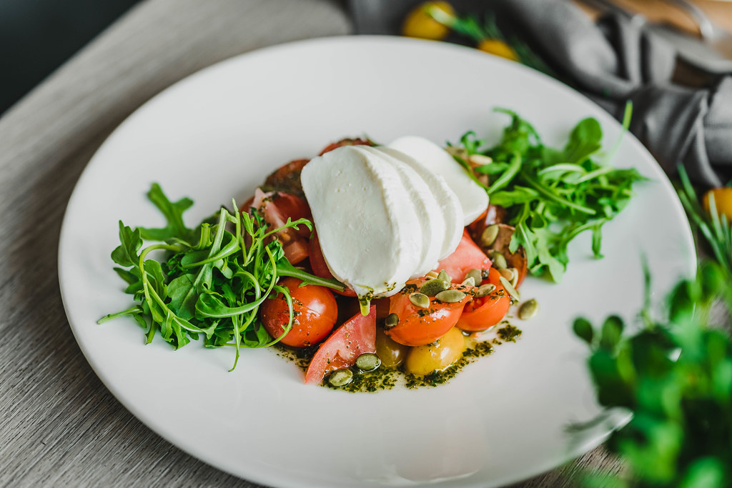 Elegant plate of burrata bruschetta with vibrant cherry tomatoes and fresh basil on a rustic wooden table