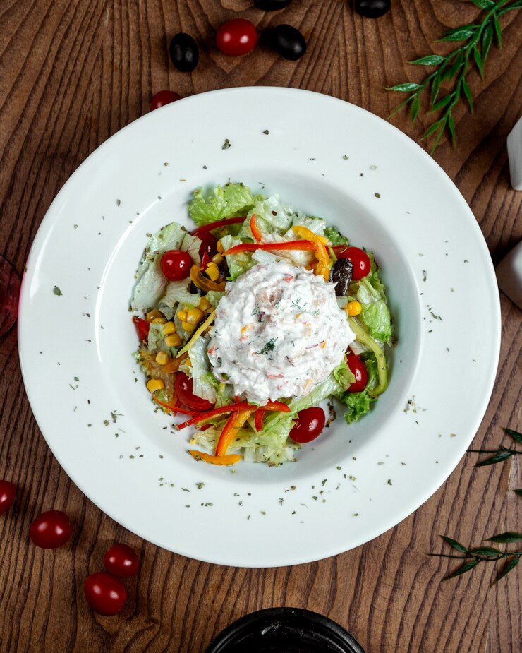 Colorful burrata salad with fresh greens, vibrant heirloom tomatoes, and creamy burrata cheese on a rustic wooden table.