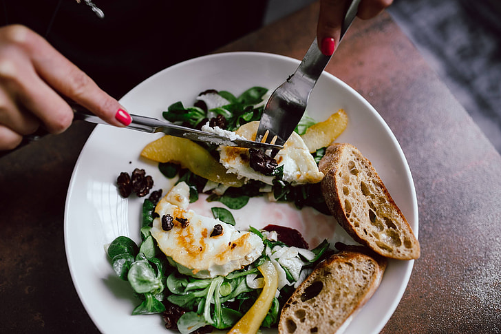 A beautifully arranged plate of Burrata with grilled peaches and basil on a rustic wooden table