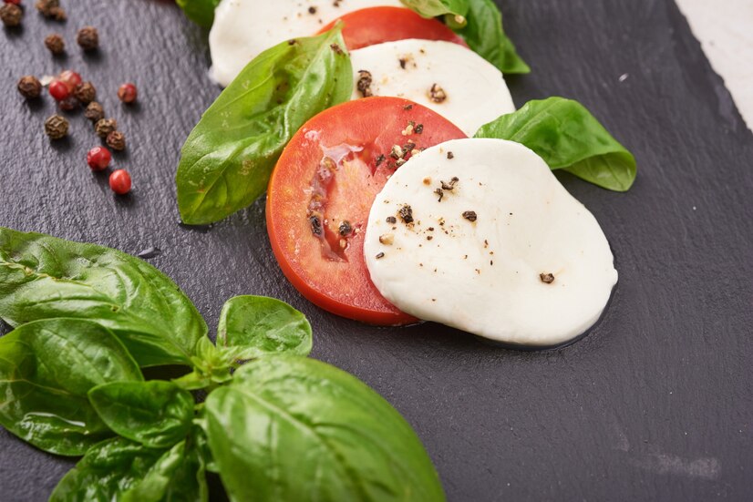 Burrata cheese on a rustic wooden board with tomatoes and basil, ready for preparation.