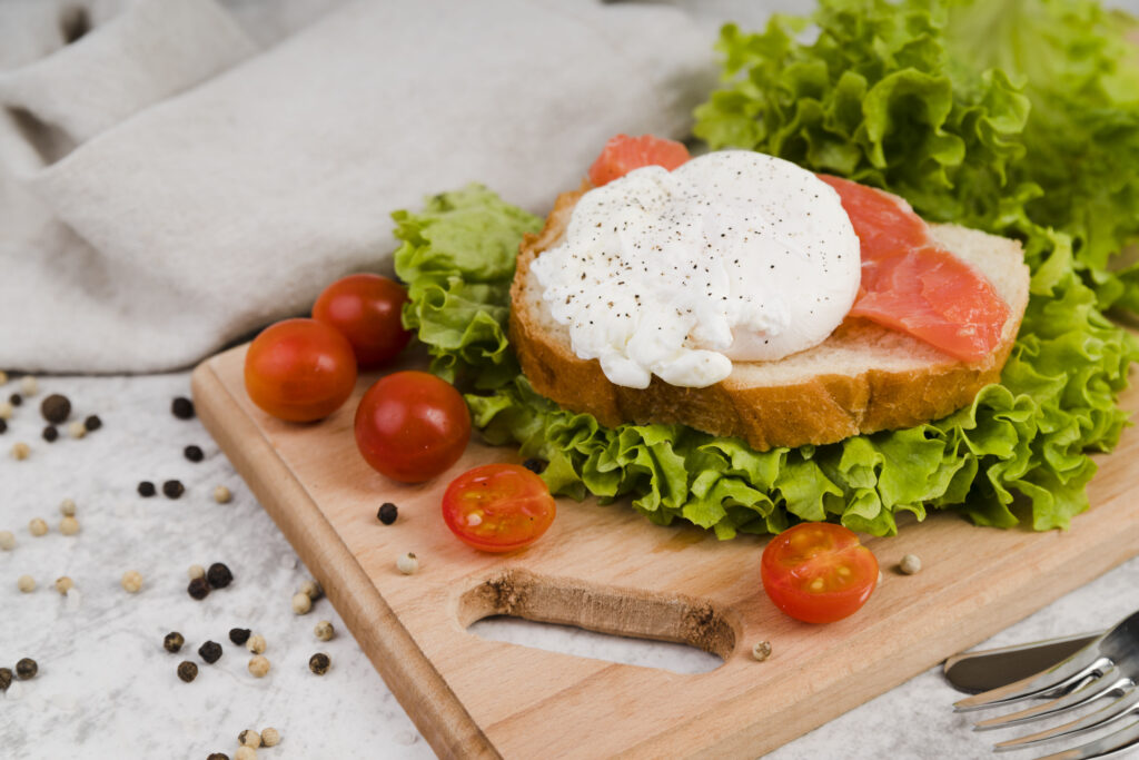 Elegant burrata toast topped with fresh herbs and ripe cherry tomatoes, served on a rustic wooden board.