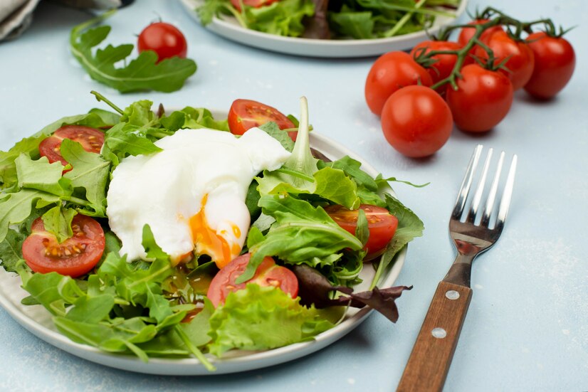 A fresh burrata salad displayed on a rustic wooden table, featuring ripe tomatoes, vibrant greens, and drizzled with olive oil and balsamic reduction