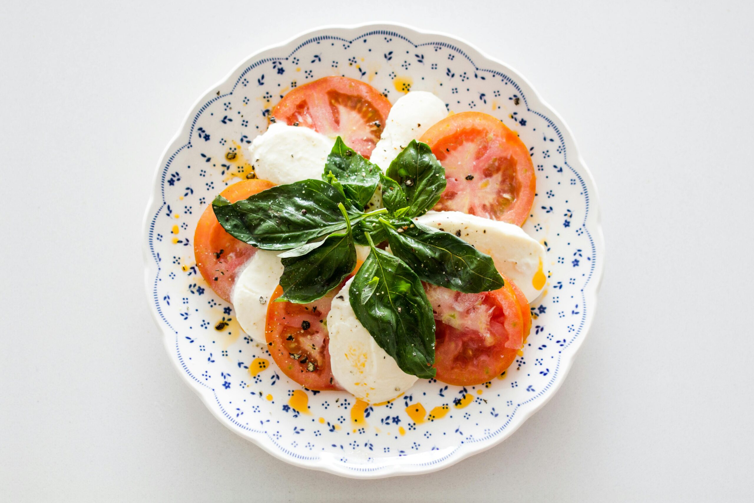 A plate of creamy burrata pasta garnished with fresh basil and cherry tomatoes, served on a rustic wooden table