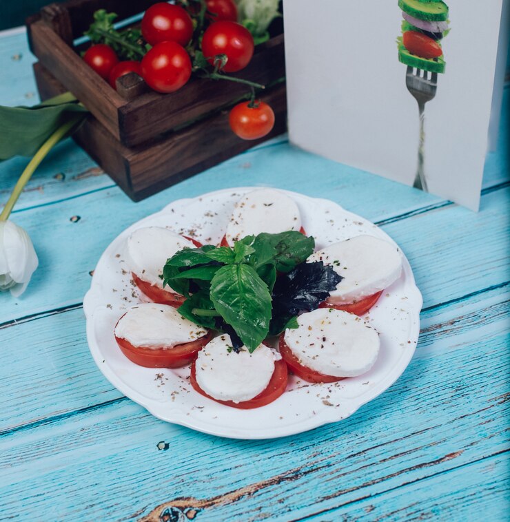 Bowl of burrata with ripe cherry tomatoes and basil, drizzled with olive oil on a rustic wooden table.